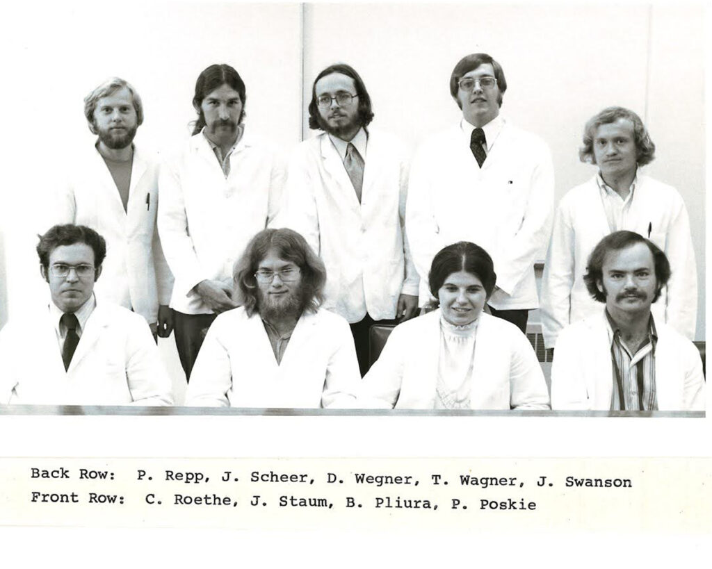 A photograph of nine people wearing white coats.