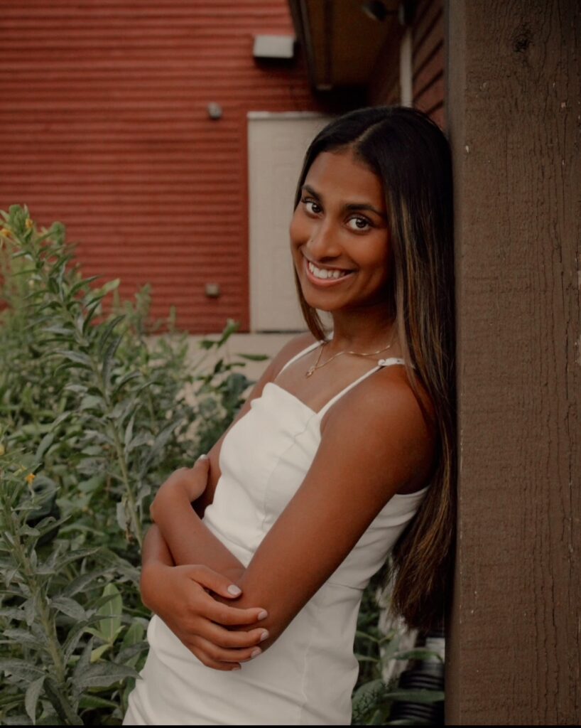 A woman poses for the camera standing against a wall.